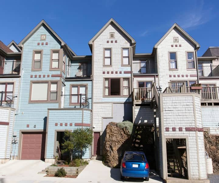 Colorful, three-story residential building with the features balconies and a rocky landscape .presenting the party wall.