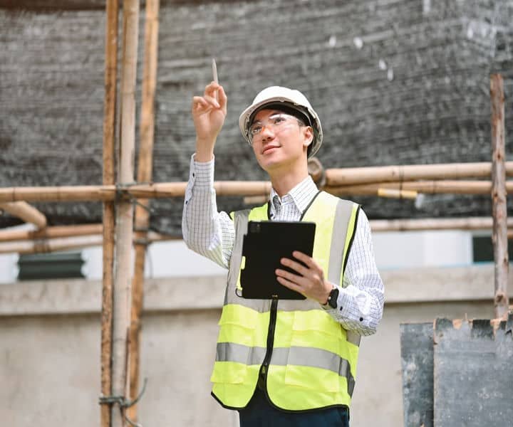 A professional inspector with a safety vest and hard hat holding a checklist, inspecting a building site.