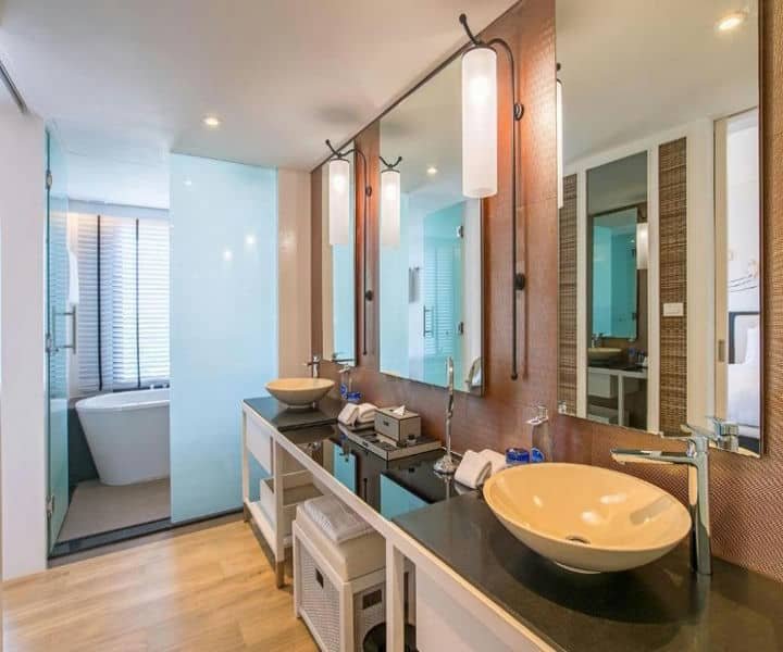 innovative bathroom featuring dual sinks, large mirrors, and a bathtub visible behind frosted glass, with stylish lighting and decor.