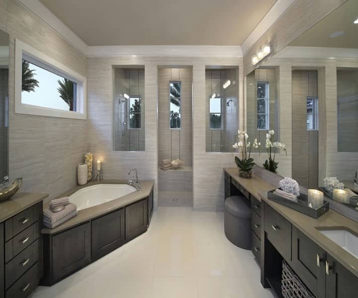 Modern bathroom with a soaking tub, sleek cabinetry, large mirrors, and natural light from windows, enhanced by elegant decor.