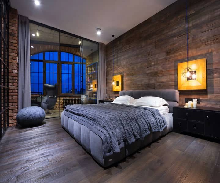 Stylish designed and reniovated cosy bedroom with a textured wood wall, a plush bed, and large windows showcasing a blue evening sky.