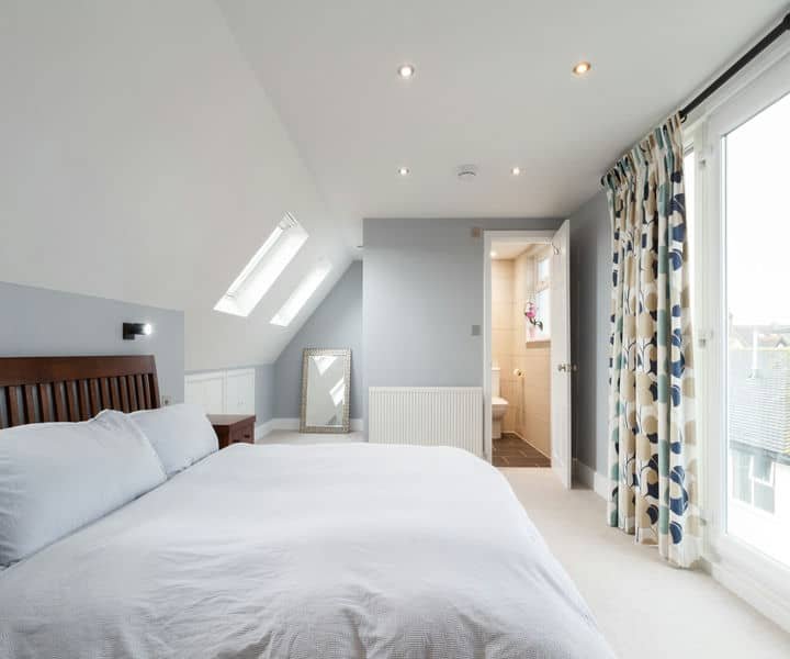 Bright attic bedroom with modern iterior, leading to an en-suite bathroom.