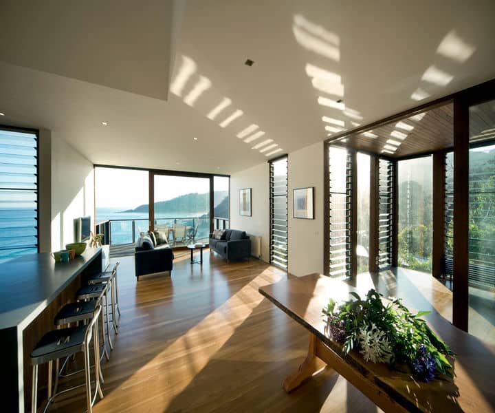 Conceptualised Bright, airy modern living room with ocean views, featuring wooden floors, and sleek furniture.