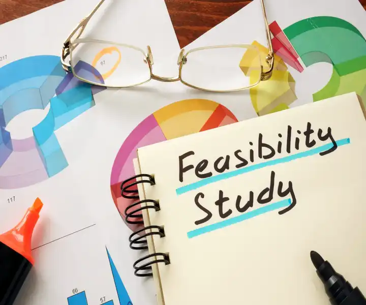 A notebook labeled "Feasibility Study," with colorful graphs on a desk, highlighting property analysis and planning.