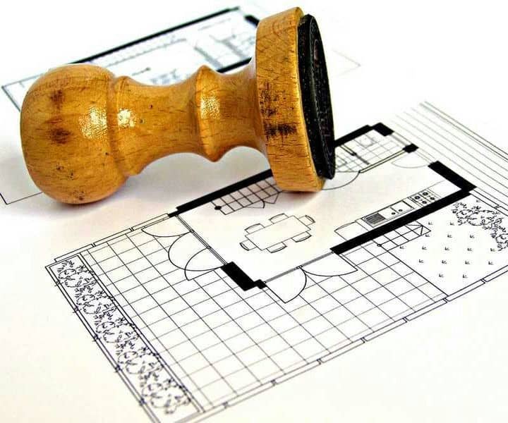 An approval stamp rests on a detailed floor plan design, showcasing a kitchen and dining area layout.