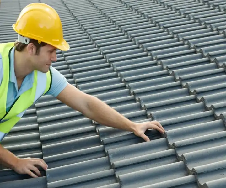 A surveyor inspects tiled roofing, ensuring proper installation and safety on a sunny day.