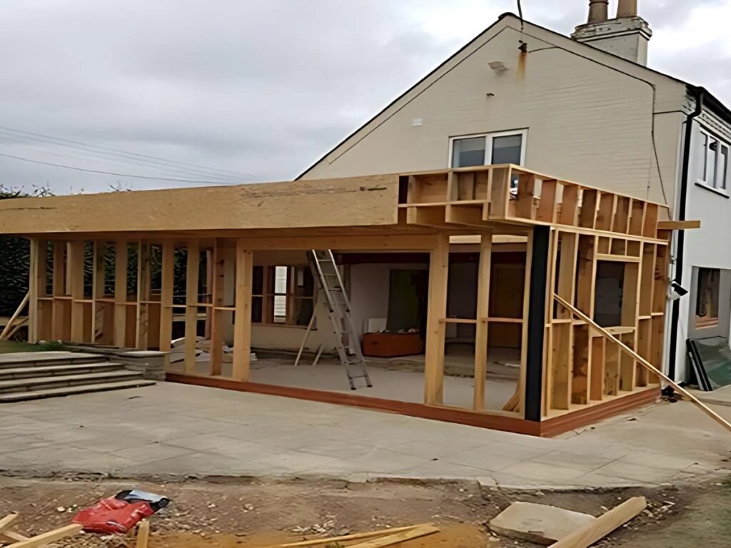 A partially constructed side home extension features wooden framing and a flat roof.
