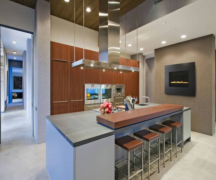 Modern kitchen design featuring sleek gray countertops, wooden cabinetry, a stylish island, and a minimalist fireplace.