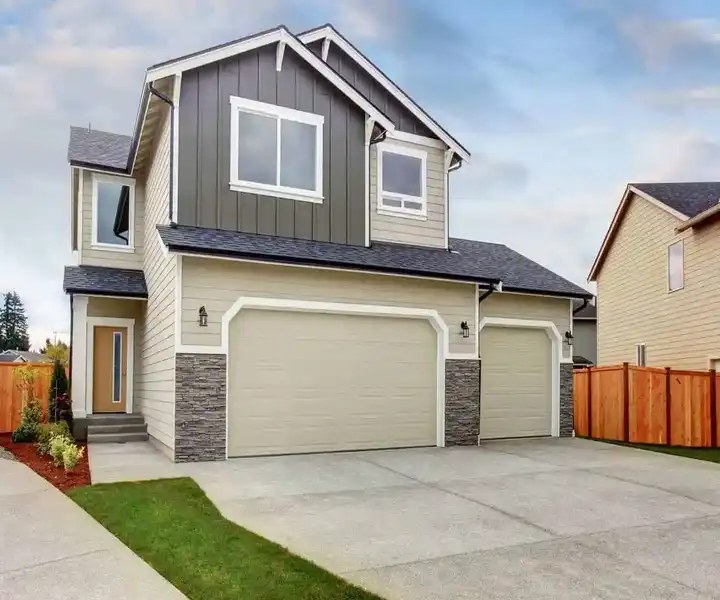 Modern two-story home with a gray and beige facade, double garage, and landscaped yard.