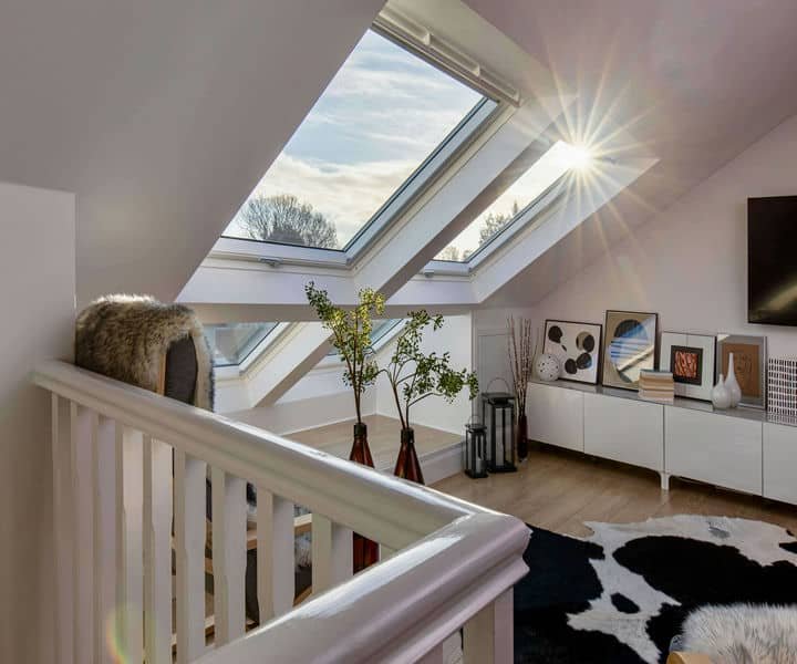 Bright velux loft, modern decor, potted plants, and a sunburst illuminating a cosy, stylish atmosphere.