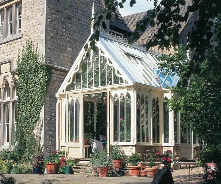 A charming glass vectorian conservatory with a white frame and pointed arches.