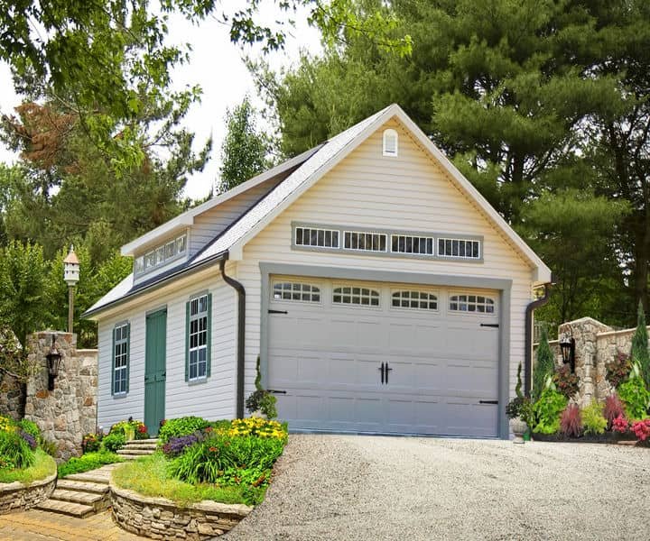 A charming white garage with green doors and a landscaped path.