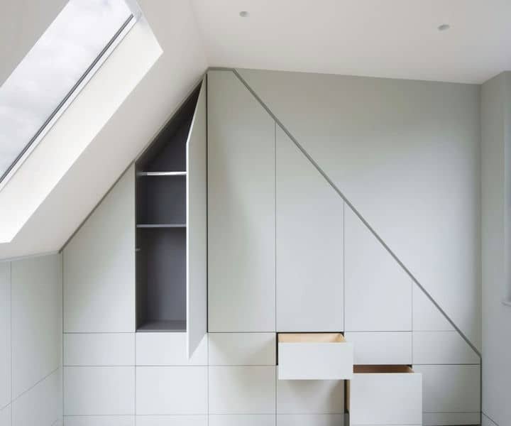Modern gray cabinetry with angled design, featuring a small open shelf, and two drawers, maximising space under a sloped ceiling desifing loft conversion storage solutions .